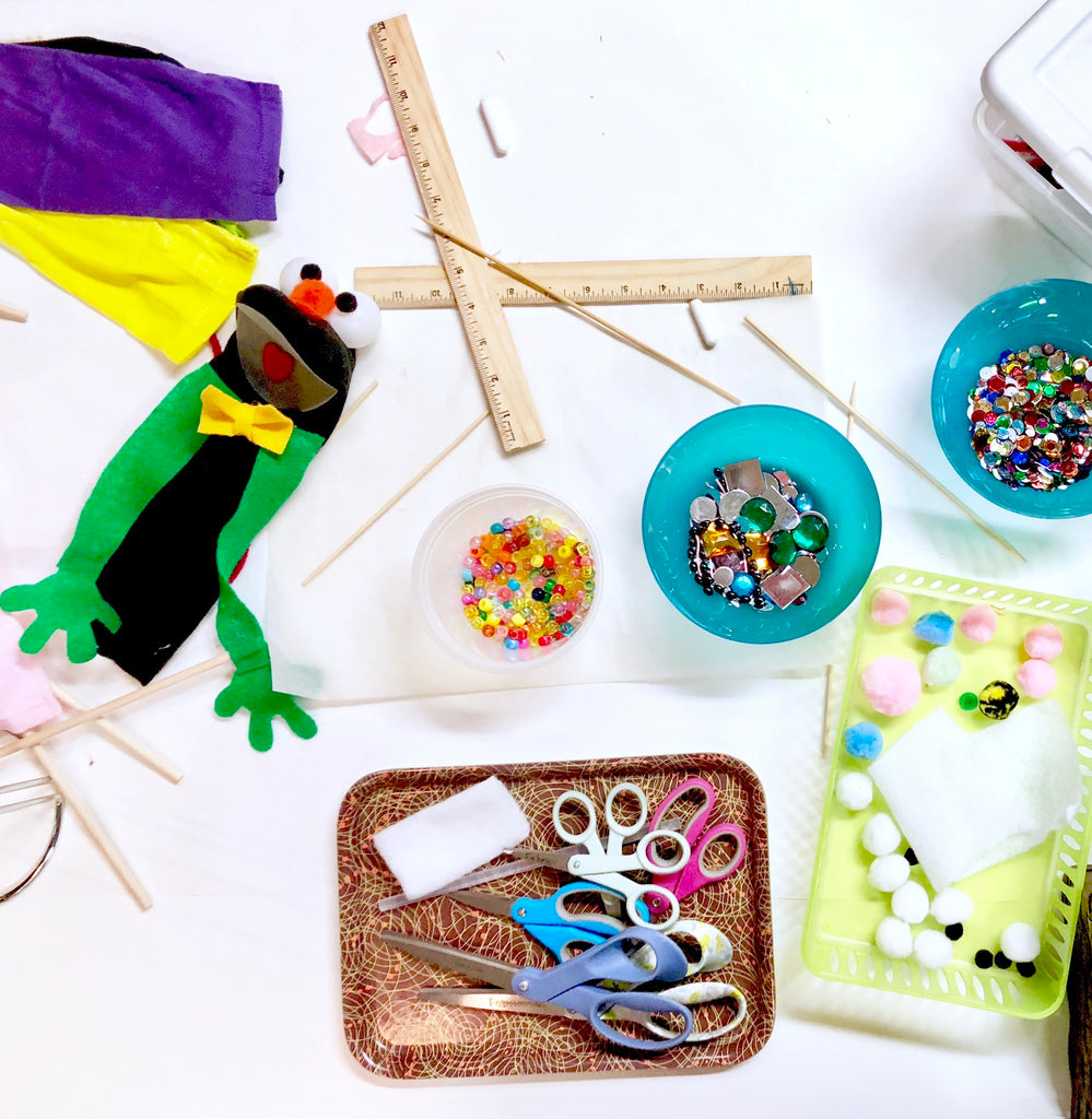 a photo of puppet making workshop supplies including a ruler scissors glitter and pom poms